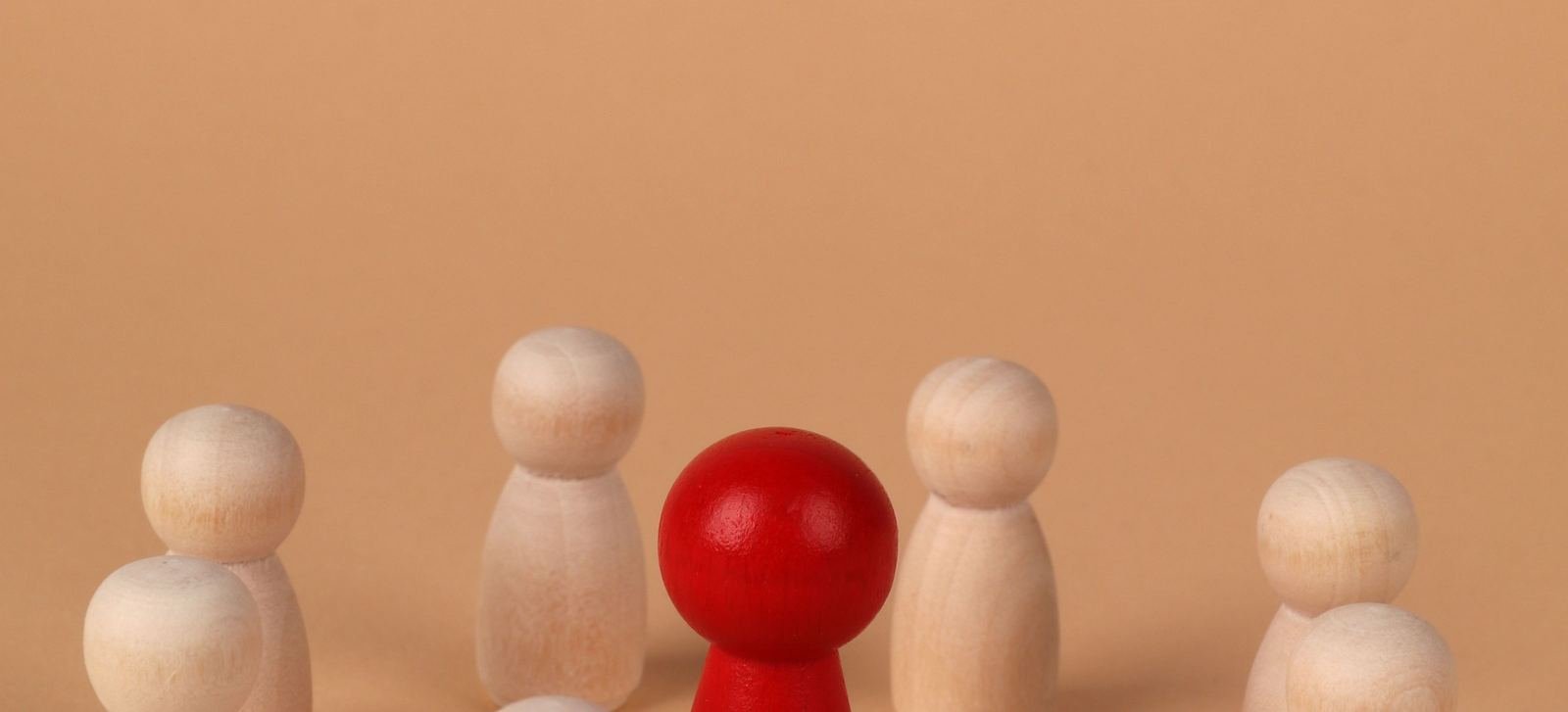 Figuras de madera dispuestas en círculo con una figura roja destacada