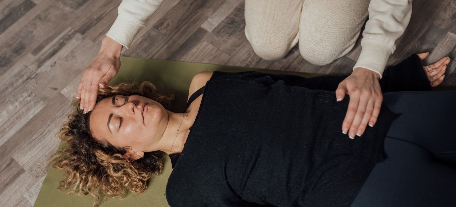 Mujer recostada con los ojos cerrados durante una sesión de Reiki
